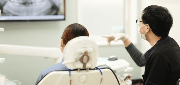 すえひろ歯科の診療室で歯の映像を見ながら患者に説明をするスタッフ